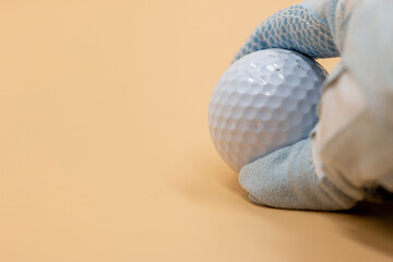 Golfer is holding golf ball on cream background