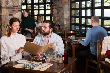 Fototapeta na wymiar Happy couple with menu at country restaurant. High quality photo