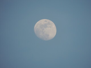 full moon with a faint haze light on a blue sky at sunset