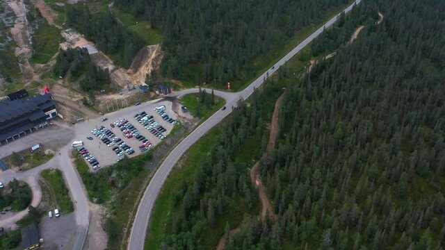 Aerial view of cars driving on the Yllas scenic road passing the Y1 Ski shop at the slopes of Yllastunturi fell, in Lapland - reverse, drone shot