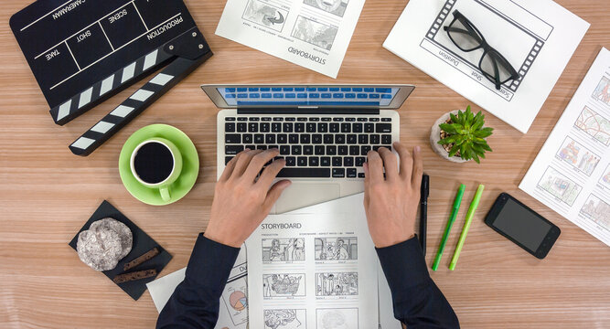The hands of the men sort out the storyboards. A top view of the work desktop