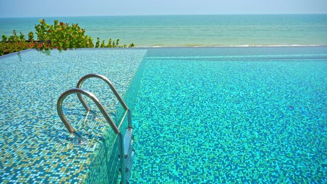 An empty resort pool with the ocean in the background.