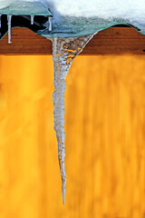 Naklejka na ściany i meble A large icicle of ice grew out from under the eaves of the roof