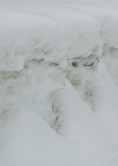 faces in white snow bank with fresh snow ploughed to the side abstract vertical format ridges and...