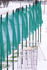 Protective fencing of a football field made of plastic mesh on a cold winter day