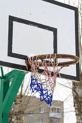 An old outdoor basketball shield with a basket with a torn net
