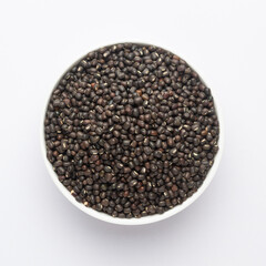 Close up of Organic Black Gram (Vigna mungo) or whole black urad on a ceramic white bowl. Top view 