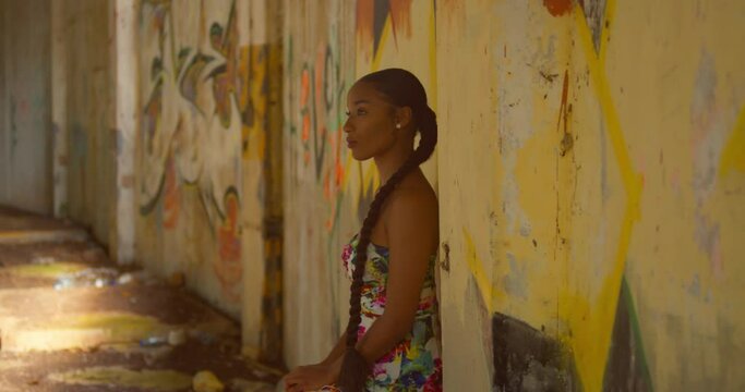 Caribbean girl stands on a graffiti wall at an abandoned building in the Caribbean