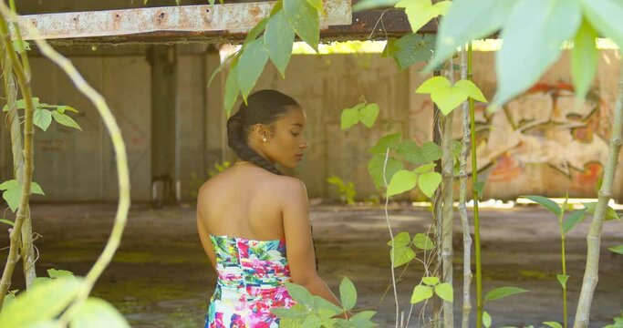 A model sits in the window of an abandoned warehouse with grafitti art in the background