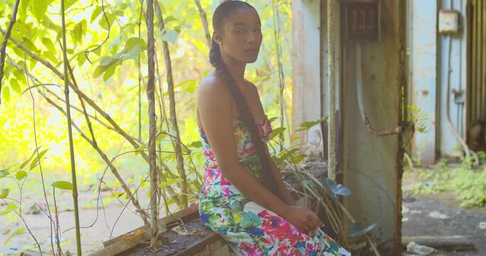Sexy young woman turns around while sitting in the window of an abandoned warehouse