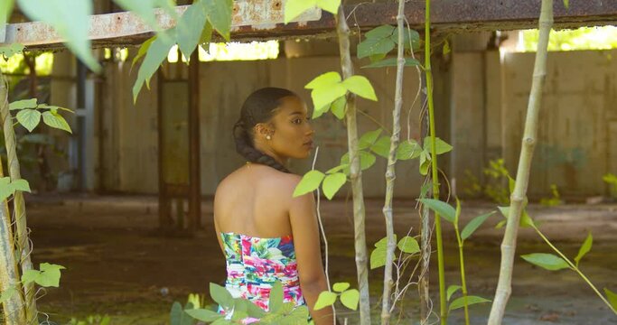 A young Caribbean Queen turns and smiles while sitting in the windows of an abandoned warehouse