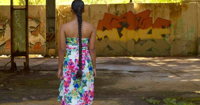 A model walks toward grafitti art on the wall at an abandoned warehouse