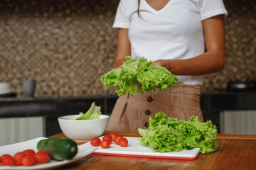 Healthy Food - Vegetable Salad. Diet. Dieting Concept. Young woman preparing vegetable salad in her kitchen, cropped face
