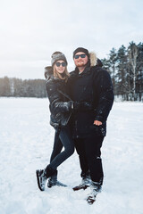 Portrait of a joyful man and woman embracing and posing together in nature landscape in winter forest.