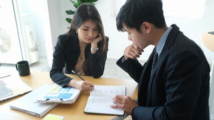 Two young business people analyzing financial figures denoting the progress in the work of the company.