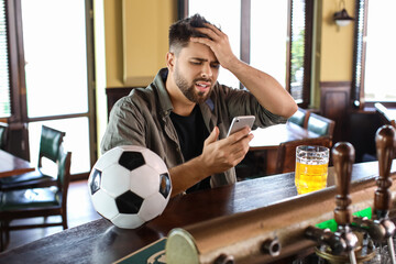 Sad young man after losing of his sports bet in pub