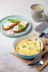 Healthy breakfast - omelette with green onions, toast with cream cheese and vegetables, coffee