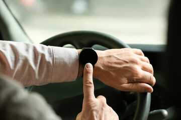 Young man with modern smart watch driving car