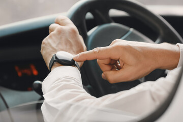 Young man with modern smart watch driving car