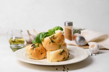 Plate with fresh bread and garlic on light background, closeup