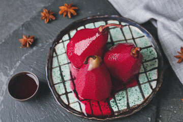 Plate with sweet poached pears in red wine on dark background