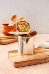 Tin can of boiled condensed milk on color background