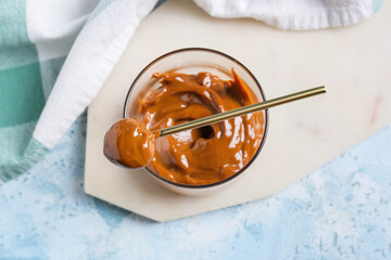 Bowl of boiled condensed milk on color background