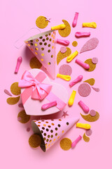 Festive composition with party hats and gift on color background