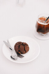 Chocolate cookies on a white table top with a blurry black coffee in the background.