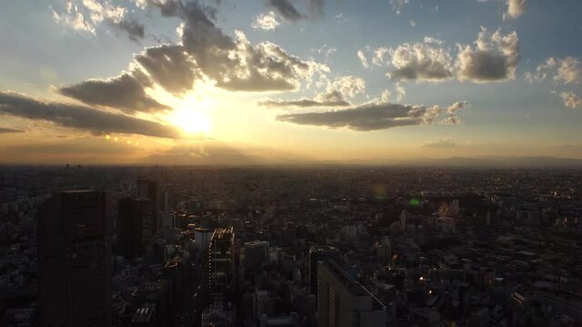 TOKYO, JAPAN : Aerial high angle sunrise CITYSCAPE of TOKYO. View of rising sun and dramatic clouds around Shibuya. Japanese urban city life and nature concept. Long time lapse video, night to morning