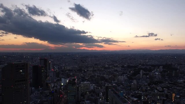 TOKYO, JAPAN : Aerial sunrise CITYSCAPE of TOKYO. View of rising sun and dramatic clouds around Shibuya. Japanese urban city life and nature concept. Long time lapse tracking video, night to morning.