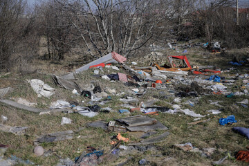 Shallow depth of field details of garbage and construction debris scattered all around an empty lot in Bucharest, near a makeshift shelter.