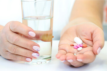 a woman drinks pills and drinks a glass of water