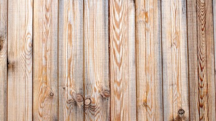 light wooden background of planed planks in the structure of a single surface, with a pattern of smooth lines of natural wood, unpainted wooden fence starting to darken due to aging
