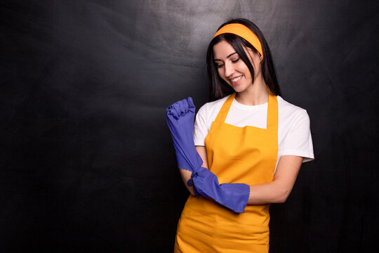 Cheerful housewife in apron putting on gloves