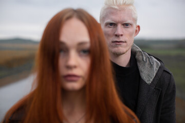 portrait of a young couple with a focus on an albino guy who stands behind a red-haired girl. High quality photo