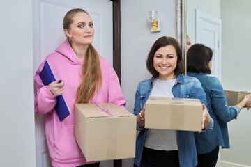 Delivery of goods, two women with cardboard boxes near front door of house