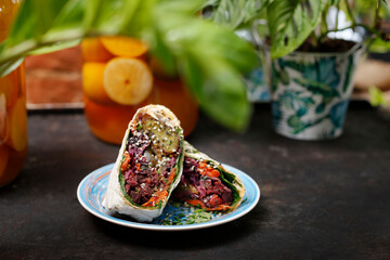
Falafel in pita bread. Vegetarian street food. Tasty colorful healthy dish served on a background of green plants. Suggestion to serve the dish. Culinary photography.