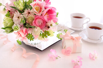 Beautiful bouquet of pink spring flowers in glass vase. Gift box with pink bow. Happy mothers day concept.  春のフラワーアレンジ 母の日