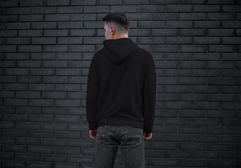 Тemplate of black men's clothing with long sleeves on a young guy on a brick wall background,...