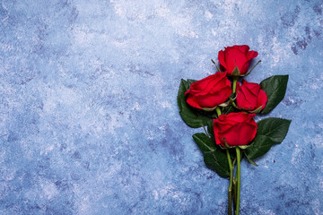 Bunch of red roses on a blue textured background with copy space and room for text