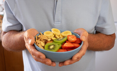 Senior man ready to eat a salad of fresh and dried fruits. Breakfast or lunch time, healthy eating