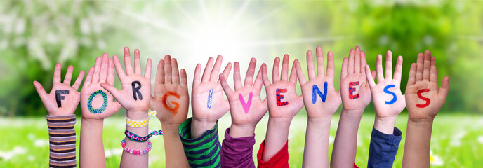 Children Hands Building Colorful English Word Forgiveness. Sunny Green Grass Meadow As Background