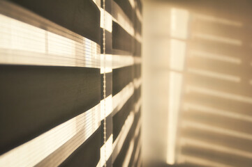 Sun shining through window blinds throwing shadows on the wall