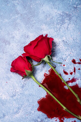Red roses on a blue textured background with a pool of splattered blood with copy space and room for text