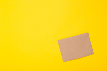 Sheet of craft paper brown color on yellow background. Clean envelope. Handmade hobby material. Wrapping. Handicraft goods store. Recyclable. Card with copy space and free text place. Natural. Eco