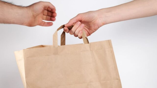 man hand give craft food paper bag to woman hands, Food delivery, takeaway, shopping online concept. 4k resolution.