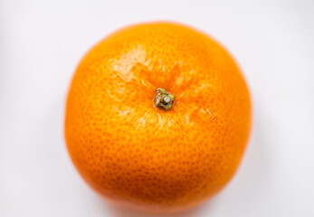 One bright ripe orange glossy tangerine in orange peel on white background. Top view. Close-up, macro