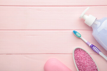 Bottle of pink shower gel, soap, bath salt and toothbrush on pink background