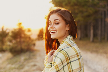 happy woman near coniferous forest road plaid sunset